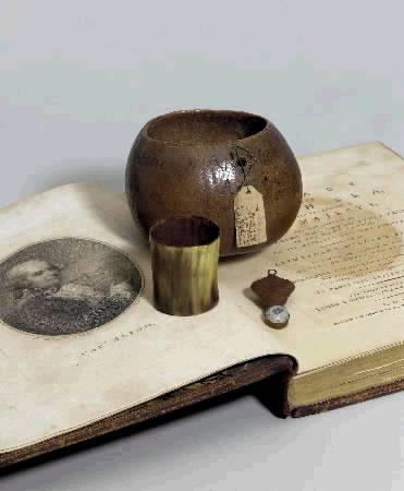 An undated photograph distributed July 18, 2002 shows a selection of relics up sold at auction today by Christie's belonging to Captain William Bligh, which he used to help save his crew after being set adrift by the Bounty mutineers in April 1789. They include a coconut, a bullet and a beaker used to measure out daily food allowances for each of his men and are displayed on top of Bligh's official account of the voyage, published in 1792