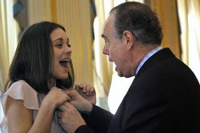 French actress Marion Cotillard (L) reacts as French Culture Minister Frederic Mitterrand accidentally pricks her with the pin while awarding her the Chevalier of Arts and Letters during a ceremony at the Culture Ministry in Paris March 15, 2010.  Photo by Philippe Wojazer