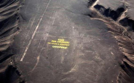 Greenpeace activists stand next to massive letters delivering the message 