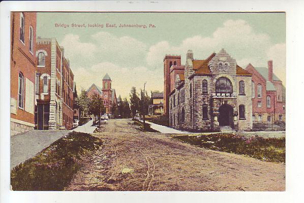 Johnsonburg, PA - Bridge Street looking east.  
On the right, the Johnsonburg National Bank, with Holy Roasry Catholic church behind.  
United Methodist Church at the top-left of the hill.
Uncle Holmes' pharmacy on the left.
Market Street is the cross street.