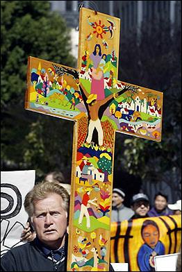 Hollywood actor and peace activist Martin Sheen holds a cross as he joins an anti-war demonstration in front of the Federal Building in Los Angeles.  Photo by Hector Mata