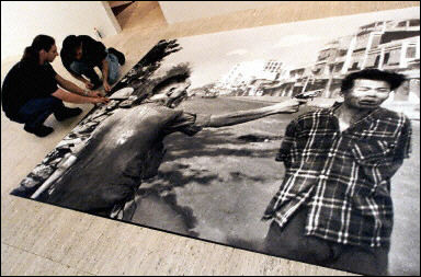 Workers at a gallery prepare a copy of the Vietnam War era picture of South Vietnamese general Nguyen Ngoc Loan shooting a Vietcong prisoner. Cartoonist Michael Ramirez used the picture as inspiration for a recent cartoon showing President George W. Bush as the victim and a figure labeled 'politics' as the shooter to a backdrop of a bombed-out city labeled 'Iraq.' The drawing sparked keen interest from the Secret Service who sent an agent round to question Ramirez, until Republican Congressman Christopher Cox stepped in to rescue the cartoonist who had meant the drawing to be supportive of Bush  Photo by Greg Wood