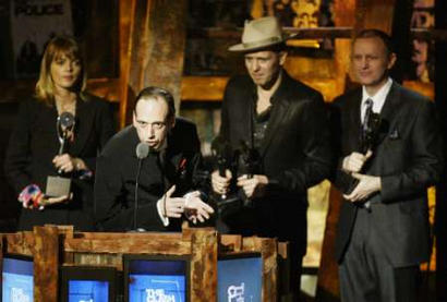 Mick Jones (2NDL) of the rock band The Clash, speaks as Clash bassist Paul Simonon (2ndR) drummer Terry Chimes and Lucinda Strummer, wife of the late lead singer Joe Strummer, look on as The Clash were inducted into the Rock and Roll Hall of Fame at New York's Waldorf Astoria Hotel, March 10, 2003. Joe Strummer, the lead singer of the clash, died in 2002. The Clash wereinducted along with Elvis Costello and Attractions, The Police, The Righteous Brothers, Mo Ostin and ACDC.  Photo by Mike Segar