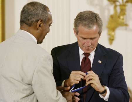 Actor and comedian Bill Cosby takes the Presidential Medal of Freedom from U.S. President George W. Bush as Bush struggles with it after not being able to latch it on Cosby at the Presentation of the Presidential Medal of Freedom Awards at the White House, July 9, 2002. Photo by Hyungwon Kang
