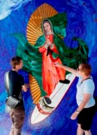 In this May 27, 2011 photo, Anthea Beletsis, right, of Encinitas, Calif., and Jules Itzkoff, of Cincinatti, Ohio, look at an image of the Virgin of Guadalupe riding a surfboard that hangs under a train bridge in Encinitas, Calif. The unauthorized artwork is drawing a mass following, and even city officials who say she must go say they too have been taken by her.   Photo by Gregory Bull 