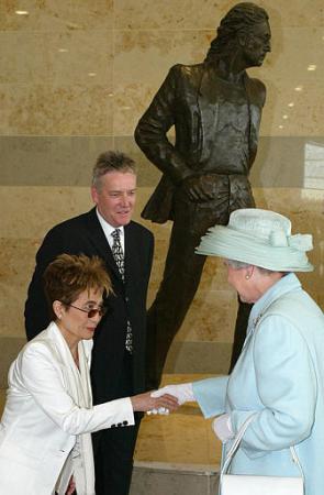 Britain's Queen Elizabeth II, right, talks with Yoko Ono, in front of a statue designed by Tom Murphy, centre, of her late husband, former Beatle John Lennon. The Queen was opening Liverpool's John Lennon Airport as she continued her Jubilee tour of the northwest of England Thursday July 25, 2002. Photo by Martin Rickett